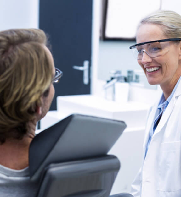 Female dentist smiling at male patient 