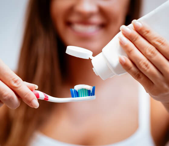 a person putting toothpaste on their toothbrush