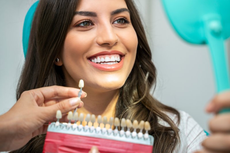 A young woman having her smile compared to a shade guide